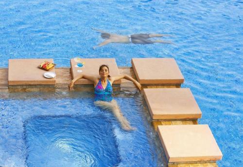 a woman laying in a pool in a swimming pool at Gulf Executive Residence in Manama