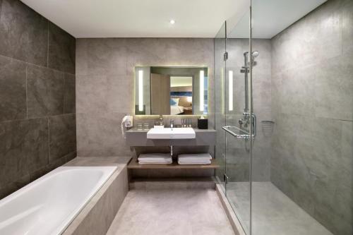 a bathroom with a tub and a sink and a shower at Novotel Jakarta Mangga Dua Square in Jakarta