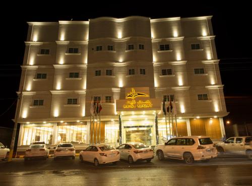 een groot wit gebouw met auto's geparkeerd voor het bij Rest Night Hotel Apartments Wadi Al Dawasir in Wadi ad-Dawasir