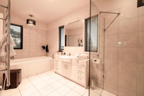 a bathroom with a tub and a sink and a shower at Hilltop Apartments Phillip Island in Cowes