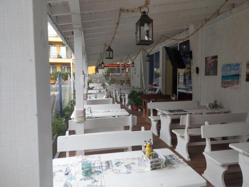 una fila de mesas y sillas blancas en un restaurante en Hotel North, en Primorsko