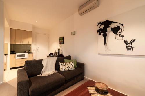a living room with a couch and a cow painting on the wall at Hilltop Apartments Phillip Island in Cowes
