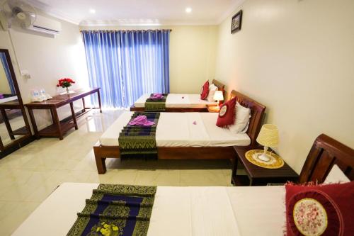 a room with three beds and a table and chairs at Blue Diamond Hostel in Battambang