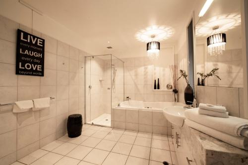 a bathroom with a tub and a sink and a shower at Hilltop Apartments Phillip Island in Cowes