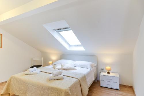 Schlafzimmer mit einem Bett mit weißer Bettwäsche und einem Dachfenster in der Unterkunft Apartment Lily in Zadar