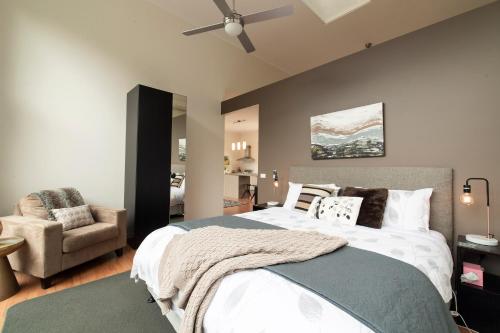 a bedroom with a large bed and a chair at Hilltop Apartments Phillip Island in Cowes