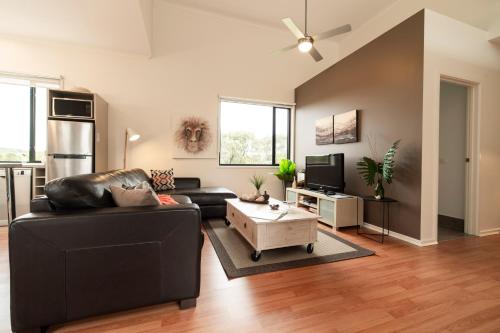 a living room with a black leather couch and a table at Hilltop Apartments Phillip Island in Cowes