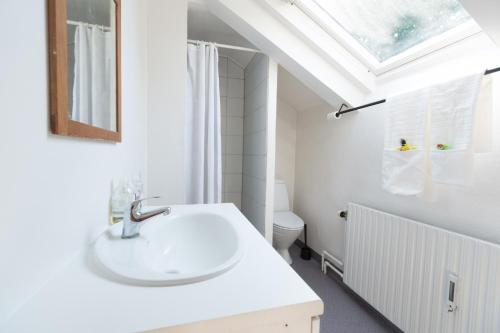 a white bathroom with a sink and a skylight at Spacious Private Apartment for Family Holiday in Stege