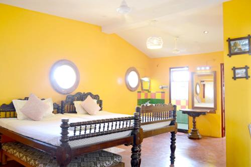 a bedroom with a bed with yellow walls at A La Villa Creole in Pondicherry