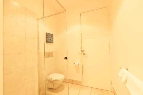 a bathroom with a toilet and a glass shower at Hilltop Apartments Phillip Island in Cowes