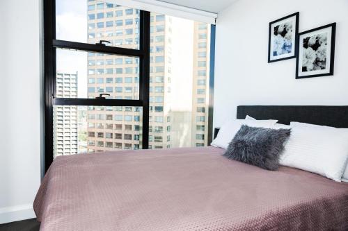 a bedroom with a bed with a large window at Executive stay Little Collins street in Melbourne
