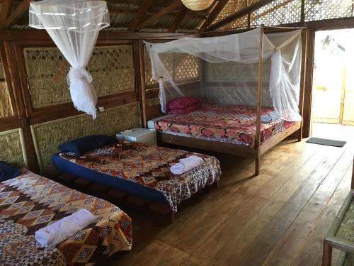 a room with two beds and a canopy bed at Beach Hut by S.A.R. in Waingapu