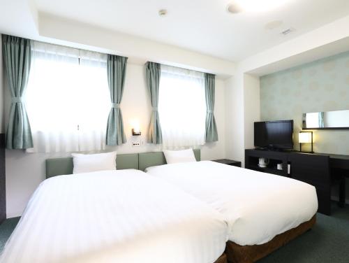 Hotel Wing International Himeji في هيميجي: غرفة نوم بسرير ابيض كبير ونوافذ