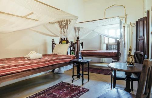 a bedroom with two beds and a table at Zanzibar Coffee House in Zanzibar City