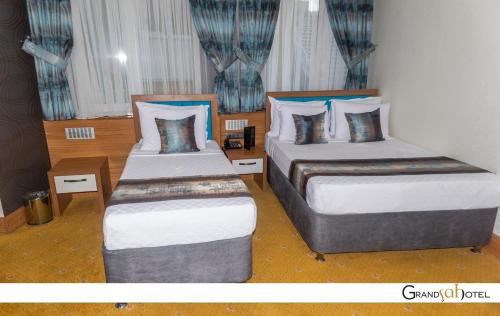 two beds in a room with blue curtains at GRAND ŞAH OTEL in Eskisehir
