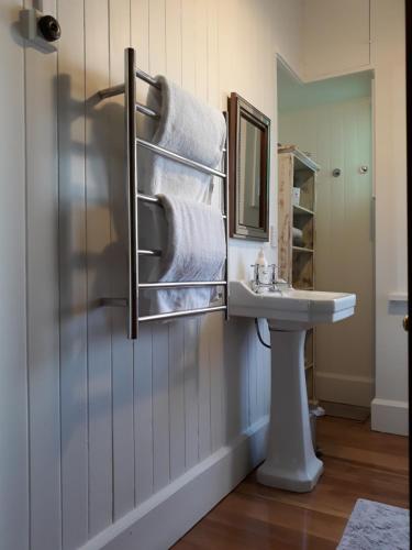 een badkamer met een wastafel, een spiegel en handdoeken bij The Wansbeck in Oamaru