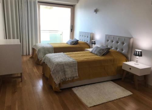 a bedroom with two beds and a window at Praia da California Apartment in Sesimbra