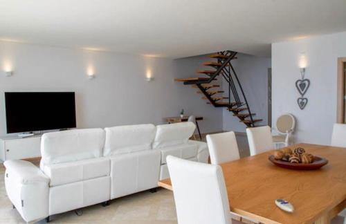 een woonkamer met een witte bank en een houten tafel bij Praia da California Apartment in Sesimbra