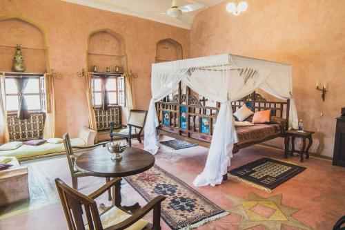 1 dormitorio con cama con dosel, mesa y sillas en Zanzibar Coffee House en Zanzíbar