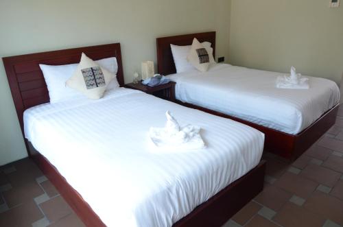 two beds with white sheets in a room at Saksiri Riverside Boutique Hotel in Vang Vieng