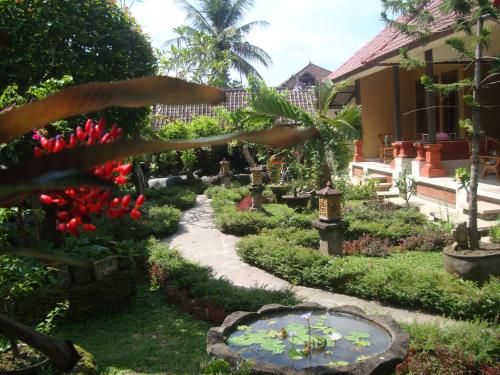 a garden in front of a house with a pond at Gusti Home Stay Ubud in Ubud
