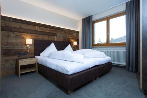 a bedroom with a large bed with a wooden wall at Apart Val Sula in Sankt Anton am Arlberg