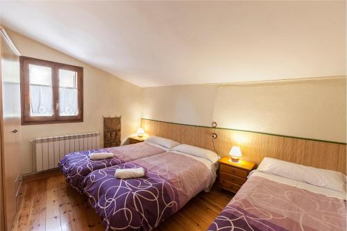 1 dormitorio con 2 camas, ventana y 2 lámparas en Cal Martí, en Farena
