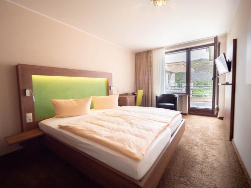 a bedroom with a bed with a green headboard and a window at Hotel Villa am Rhein in Andernach
