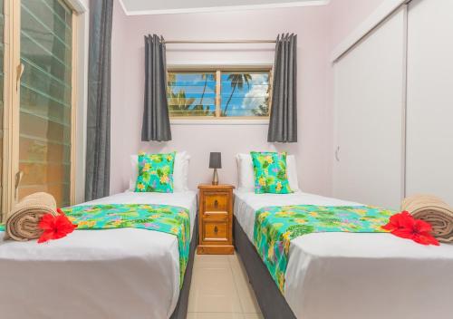 1 dormitorio con 2 camas individuales y ventana en Rarotonga GolfSeaView en Rarotonga