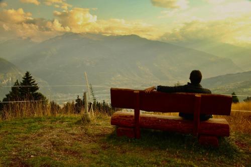 a man sitting on a bench looking at the mountains at Studio in Les Collons