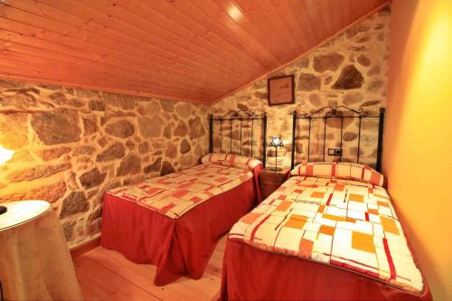 2 Betten in einem Zimmer mit einer Steinmauer in der Unterkunft Casa Porto de Quilmas in O Pindo