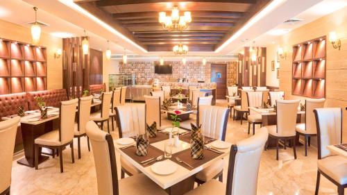 un restaurante con mesas y sillas en una habitación en The Grand Ambassador en Phagwāra