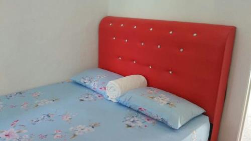 ein Bett mit zwei Kissen und einem roten Kopfteil in der Unterkunft Rehat Penginapan Famili in Kampung Kuala Besut