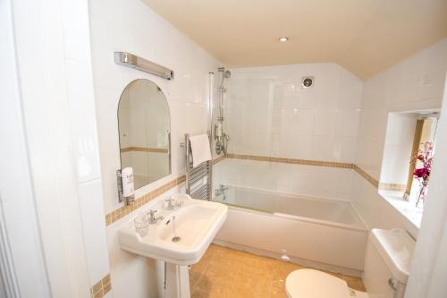 baño blanco con bañera, lavabo y aseo en NormanHurst Hotel, en Sale