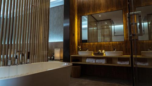 a bathroom with two sinks and a tub and a mirror at Lin Yin Art Hotel Shanghai（Pudong airport） in Shanghai