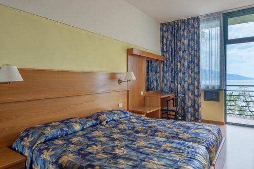 a hotel room with a bed and a large window at Centro Vacanze La Limonaia in Limone sul Garda