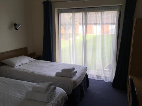 a bedroom with two beds and a window with towels at The Abbey Hotel and conference centre in Minster