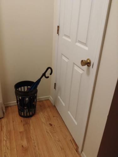 a black umbrella in a basket next to a door at Pleasant Place Rooms in Queens