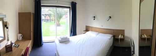 a bedroom with a bed and a large window at The Abbey Hotel and conference centre in Minster