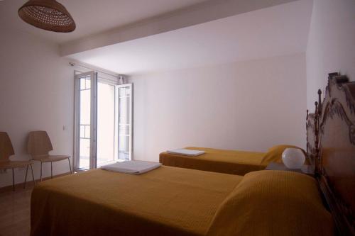 a bedroom with two beds and a large window at Casa da Tia Matilde in Sesimbra