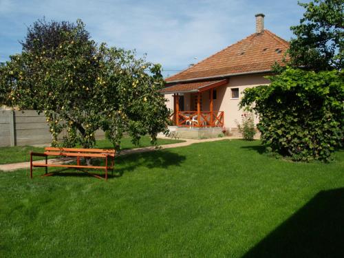 a house with an apple tree and a bench in a yard at Liliom Apartman in Gyula