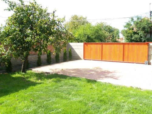 a garden with a orange fence and a grass yard at Liliom Apartman in Gyula