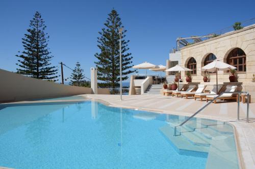 una piscina con sillas y sombrillas junto a un edificio en Macaris Suites & Spa, en Rethymno