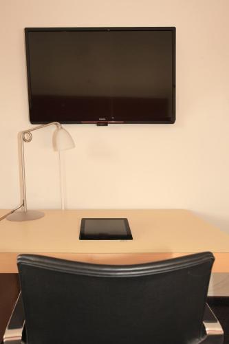a flat screen tv on a desk with a black chair at Hotel Svendborg in Svendborg