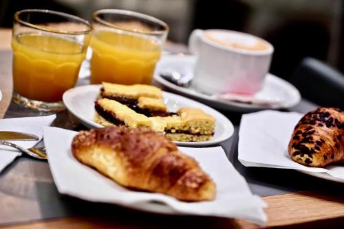 a table with plates of pastries and cups of orange juice at Hotel Centrale in Mestre
