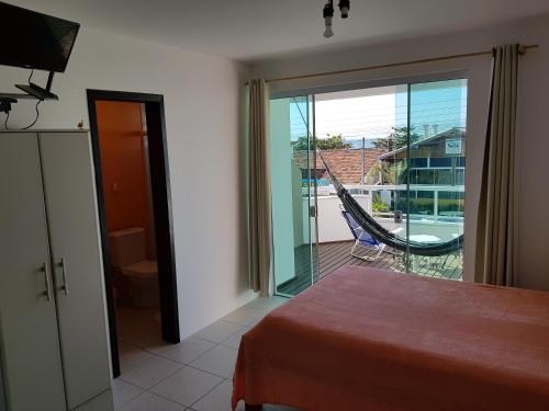 Cette chambre comprend un lit et offre une vue sur un balcon. dans l'établissement Suítesmariscal Suítes Mariscal, à Bombinhas