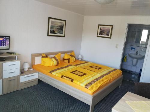 een slaapkamer met een bed met gele lakens en een wastafel bij Zingster Ostseeklause in Zingst