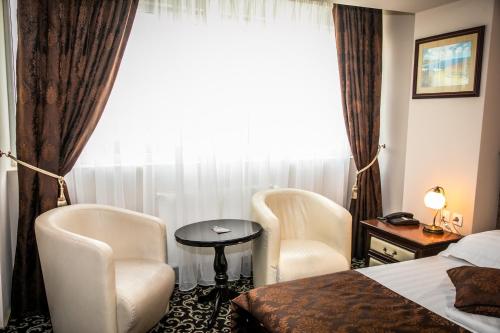 a hotel room with two chairs and a bed and a window at Hotel Megalos in Constanţa