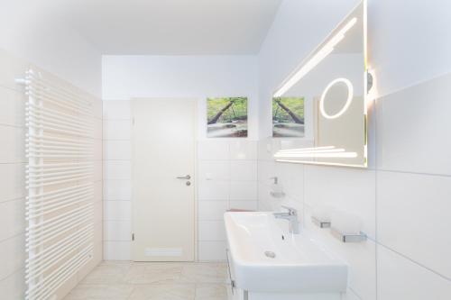 ein weißes Badezimmer mit einem Waschbecken und einem Spiegel in der Unterkunft Harzer-Bachtaeler in Benneckenstein