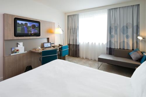 a hotel room with a bed and a tv at Novotel Leuven Centrum in Leuven